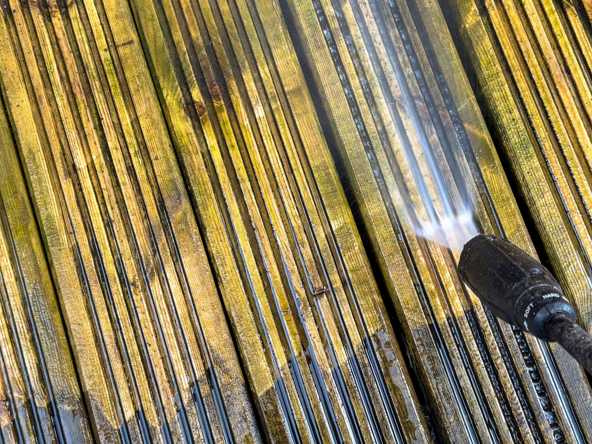 Before and after view of wooden decking cleaned by a pressure washer